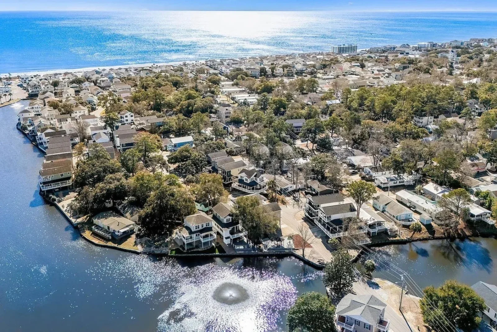 Aerial view of a Myrtle Beach neighborhood of homes along a lagoon, with the ocean beyond
