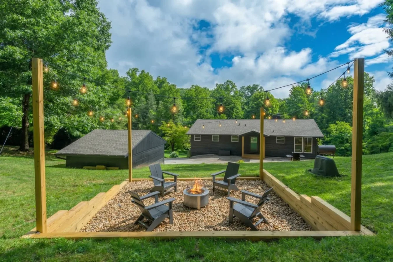 Firepit lounge area with string lights at a Leisr Stays managed property on 4.5 acres near Waynesville, North Carolina